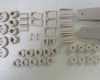 May include: A collection of off-white plastic model pieces, including wheels, connectors, and structural components.