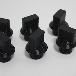 Puede incluir: Seis pomos de plástico negro con parte superior cuadrada y base redonda. Los pomos están diseñados para usarse con muebles u otros objetos.