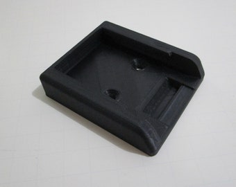 May include: A black plastic 3D printed phone stand with a slot for a phone and two holes on the top.