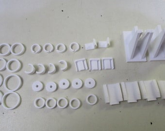May include: A set of white plastic 3D printed parts, including rings, connectors, and small rectangular pieces. The parts are arranged on a white surface.