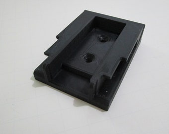 May include: Black plastic 3D printed part with two holes and a rectangular opening.
