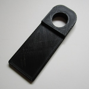 May include: A black plastic key holder with a round hole at the top. The holder is designed to be hung on a hook.