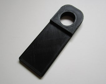 May include: A black plastic key holder with a round hole at the top. The holder is designed to be hung on a hook.
