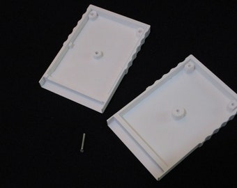 May include: Two white plastic cases with a screw. The cases have a textured edge and a small hole in the center.