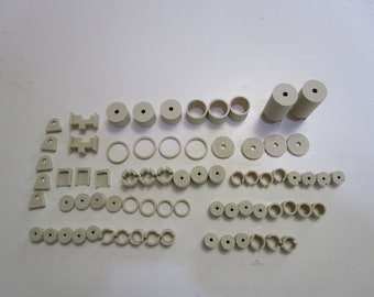 May include: A collection of beige plastic model building parts, including cylinders, rings, squares, and other shapes.