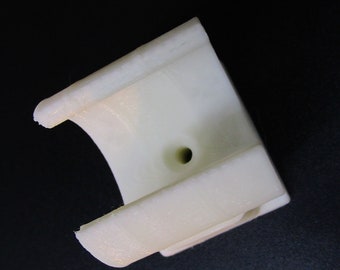 May include: White plastic 3D printed part with a hole in the center. The part is shaped like a half-circle with a flat base.