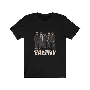 May include: Black t-shirt with a vintage-style image of five men in suits and hats. The text "WAIT A MINUTE CHESTER" is printed below the image.