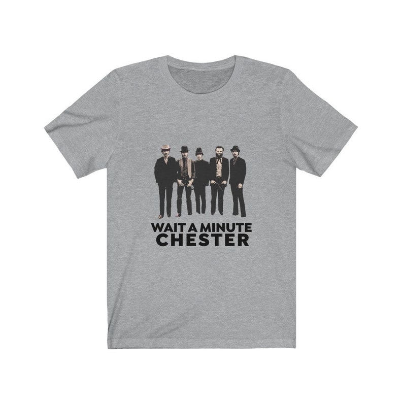May include: A gray t-shirt with a black and white image of a band of five men wearing hats and suits. The text "WAIT A MINUTE CHESTER" is printed below the image.