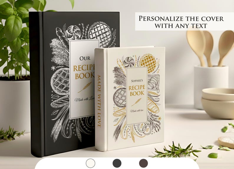 May include: Two recipe books, one black and one cream-colored, with illustrated covers featuring food-related designs. The black book reads "Our Recipe Book" and the cream book reads "Sophie's Recipe Book". Both books have the text "Made with Love".