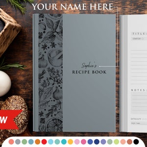 May include: A gray recipe book with a black and white illustration of herbs and spices on the cover. The book has the title "Sophie's Recipe Book" printed on the front cover.