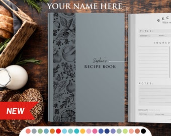 May include: A gray recipe book with a black and white illustration of herbs and spices on the cover. The book has the title "Sophie's Recipe Book" printed on the front cover.