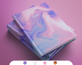 Op de afbeelding: Een stapel van drie notitieboekjes met een roze, blauwe en witte marmeren omslag. Het bovenste notitieboekje heeft de naam "Sophie" op de voorkant en een sterrenbeeldontwerp.