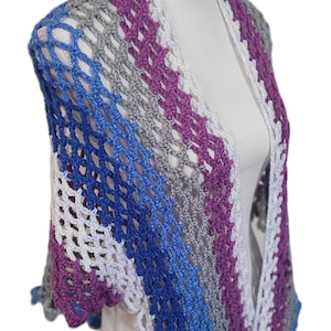 May include: A crocheted shawl with a striped pattern in shades of purple, gray, blue, and white. The shawl is made with a delicate openwork stitch.
