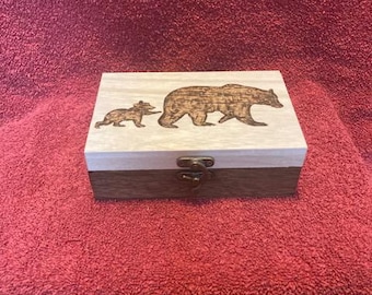 May include: A wooden box with a hinged lid and a brass latch. The lid is decorated with a woodburned design of two bears, one large and one small.