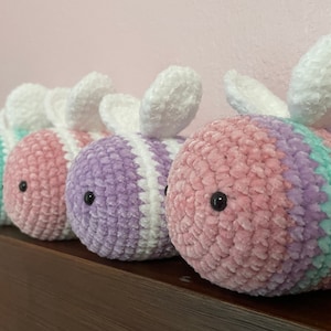 Pu&ograve; includere: Tre peluche di api all'uncinetto in diversi colori: verde chiaro, rosa e viola. Ogni ape ha ali bianche e occhi neri.