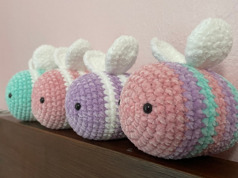 Pu&ograve; includere: Tre peluche di api all'uncinetto in diversi colori: verde chiaro, rosa e viola. Ogni ape ha ali bianche e occhi neri.