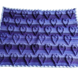 May include: A purple and blue crocheted baby blanket with a heart pattern.