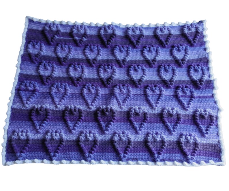 May include: A purple and blue crocheted baby blanket with a heart pattern.