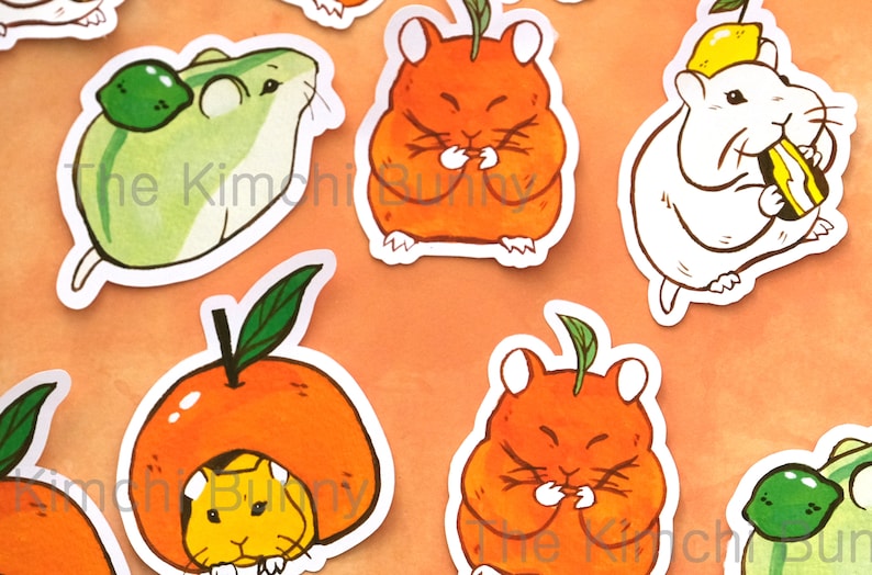May include: A set of five stickers featuring cartoon hamsters wearing fruit hats. The hamsters are in various poses, including eating, sleeping, and sitting. The fruit hats are made of orange, lemon, and lime. The stickers are printed on white paper and have a glossy finish.
