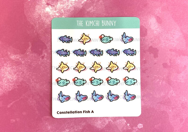 May include: A sheet of stickers featuring a variety of colorful fish designs. The stickers are arranged in rows and columns, with each fish having a unique design. The stickers are labeled "Constellation Fish A" and "The Kimchi Bunny".
