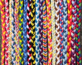 May include: A collection of colorful braided friendship bracelets in various patterns and colors, including red, blue, yellow, green, white, and black.