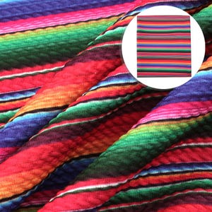 May include: Colorful striped fabric with a textured surface. The fabric has a repeating pattern of red, orange, yellow, green, blue, and purple stripes.