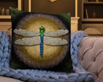 May include: A throw pillow featuring a black background with a green, blue and white dragonfly in the centre. The dragonfly is surrounded by a golden circle.