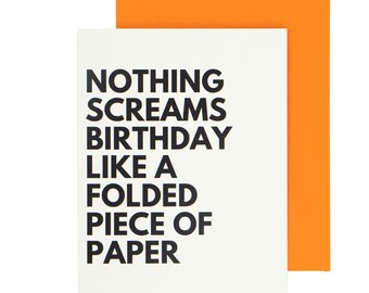 May include: A white birthday card with the text "NOTHING SCREAMS BIRTHDAY LIKE A FOLDED PIECE OF PAPER" in black. It is accompanied by an orange envelope.
