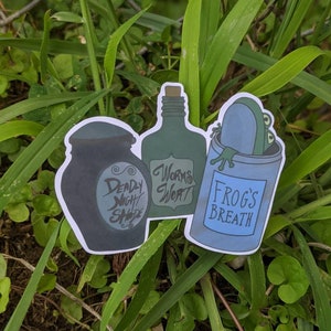 May include: Three stickers featuring potion bottles with whimsical labels. The labels read "Deadly Night Shade", "Worms Wort", and "Frog's Breath".