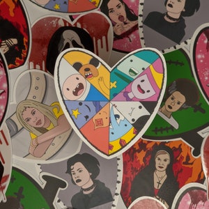 May include: A collection of heart-shaped stickers featuring various characters and designs. The stickers include a cartoon heart divided into eight sections with different characters from the animated series Adventure Time, a sticker with a woman with dark hair and a black choker, and a sticker with a woman with blonde hair and a yellow shirt.