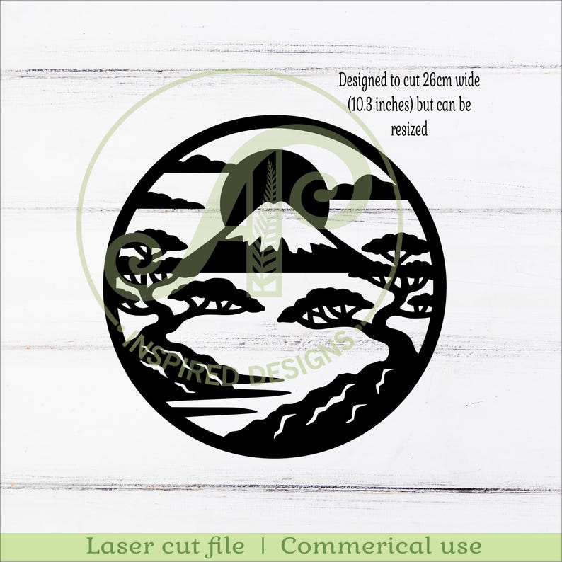 May include: Black laser-cut design of a mountain landscape within a circle. The design includes trees, a mountain, a sun, and clouds. The text says "Designed to cut 10.3 inches wide but can be resized." The bottom text says "Laser cut file | Commerical use."