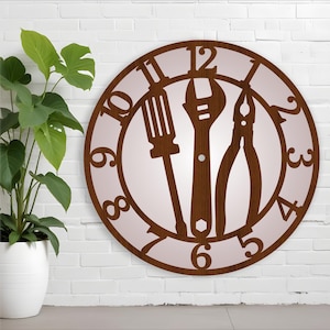 Könnte beinhalten: Braune Holz-Wanduhr mit Schraubendreher, Schraubenschlüssel und Zange als Zeiger. Das Zifferblatt hat traditionelle Zahlen. Links ist eine Topfpflanze. Die Uhr hängt an einer weißen Ziegelmauer.