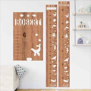 Puede incluir: Gráfico de crecimiento de madera con temática marina. El gráfico presenta el nombre "ROBERT" y una escala de altura en centímetros. Elementos decorativos incluyen criaturas marinas como ballenas, caballitos de mar y pulpos. Para habitación infantil.