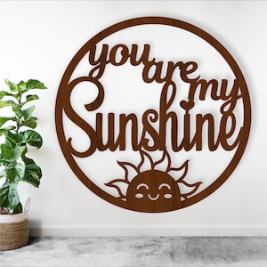 May include: A brown wooden circle with the words "You are my sunshine" in a decorative font. A stylized sun with a smiling face is below the text.