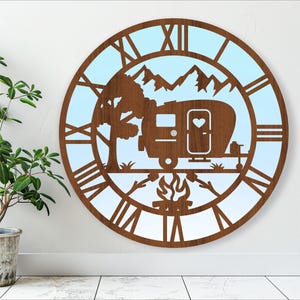 May include: A wooden clock with a blue background and a silhouette of a camper, mountains, a tree, and a campfire. The clock face has Roman numerals.