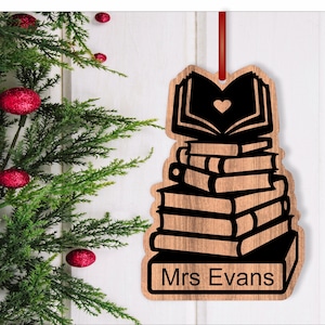 May include: Wooden Christmas ornament shaped like a stack of books with a heart on the top book. The ornament is personalized with the name "Mrs. Evans".