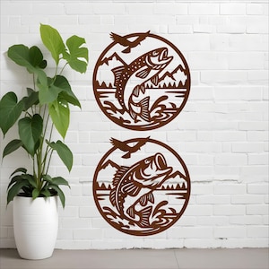 May include: Two brown metal wall art pieces featuring a fish leaping out of water within a circular frame. The design includes mountains, water, and a bird silhouette, perfect for a rustic or outdoors-themed decor.