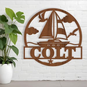 May include: A wooden cutout of a sailboat with a star and the name "COLT" in a circle. The sailboat is on a wave with seagulls flying above.