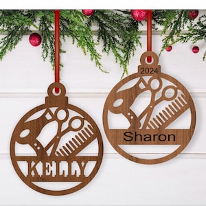 Könnte beinhalten: Zwei braune Weihnachtsbaumschmuck aus Holz mit einem Design aus Haartrockner, Schere und Kamm. Die Ornamente sind mit den Namen "Kelly" und "Sharon" personalisiert.