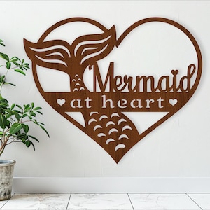 May include: Brown wooden heart-shaped sign with a mermaid tail design and the text "Mermaid at heart" with a heart symbol on each side of the text.