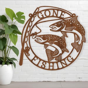May include: A brown metal sign with the words "Gone Fishing" and two fish silhouettes. The fish are facing opposite directions and have a fishing rod and lure in the background.