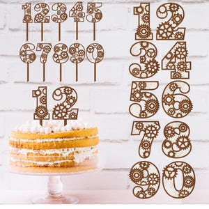 May include: A set of ten wooden cake toppers shaped like numbers 1 through 10. Each number is decorated with a steampunk design featuring gears and cogs. The numbers are brown and are arranged in two rows on a white background.