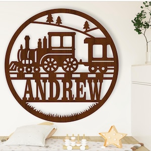 May include: A brown wooden round sign with a cutout design of a train engine and a train car. The sign has a brown woodgrain finish and the words "ANDREW" are cut out below the train. The sign is perfect for a child's room.