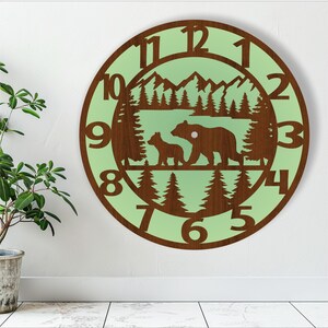 May include: A wooden clock with a green background and brown bear silhouettes. The clock face features Roman numerals and a forest scene with trees and mountains.