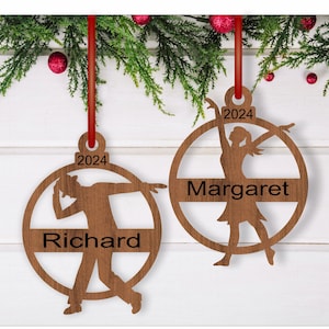 May include: Two wooden Christmas ornaments with silhouettes of a man and a woman dancing. The ornaments are round and have a red ribbon attached. The year 2024 is printed on each ornament, along with the names "Richard" and "Margaret".
