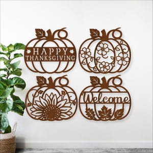 May include: Four brown pumpkin-shaped wall decorations. One says "Happy Thanksgiving", another has floral designs, a third has a sunflower, and the last says "Welcome" with leaves. The decorations are made of a dark brown material.