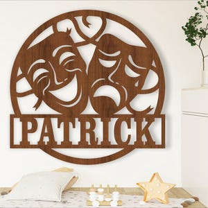 May include: A brown wooden circle with two masks, one smiling and one frowning, and the name "Patrick" written below.