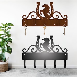 May include: A wooden key holder with a horse silhouette and horseshoe design. The holder has five hooks for hanging keys. The holder is brown and has a distressed finish.