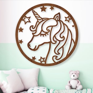 Peut inclure: Une découpe en bois brun d'une licorne avec un motif d'étoiles autour du bord. La licorne est tournée vers la gauche et a un œil fermé.