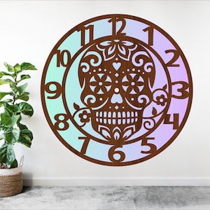 Könnte beinhalten: Dekorative Wanduhr aus Holz mit einem Sugar-Skull-Design. Die Uhr hat einen braunen Holzrahmen mit einem blau-violetten Farbverlauf. Der Sugar Skull ist aufwendig mit floralen und herzförmigen Mustern verziert.